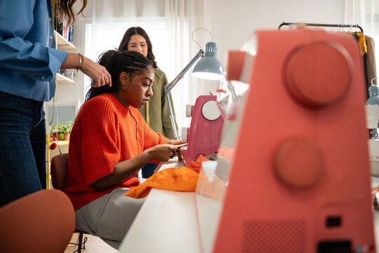 Multiethnic women sewing garment in bright design atelier