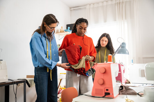 Multiethnic women sewing garments in fashion atelier