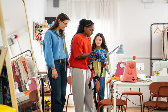 Multiethnic women in sewing atelier checking garment fit