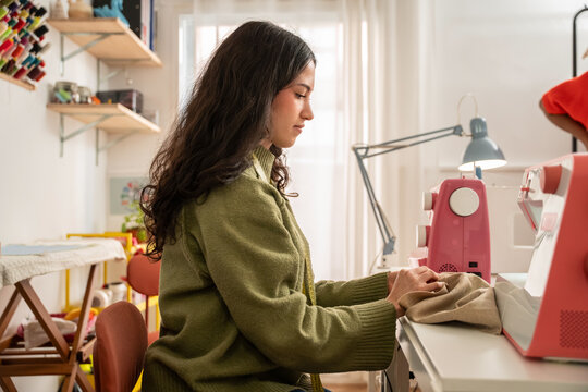 Woman sewing garment at fashion atelier with machine