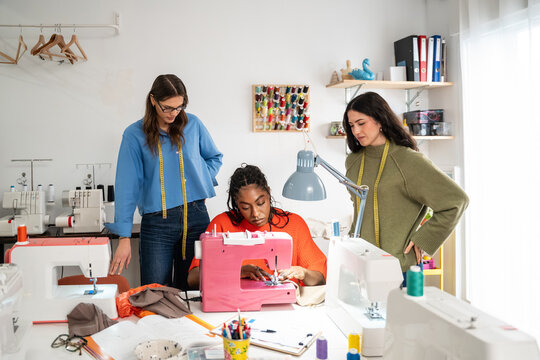 Teacher guiding students in a sewing workshop classroom