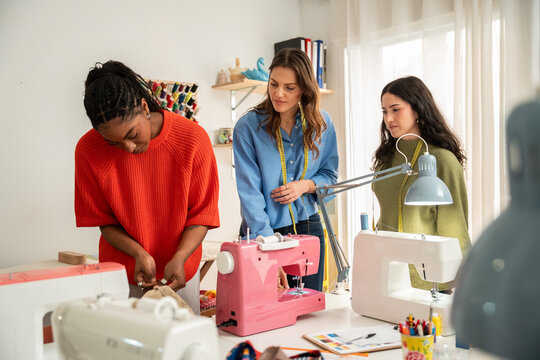 Multiethnic women sewing in bright fashion atelier