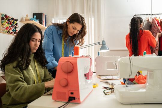 Multiethnic women sewing garments in bright fashion atelier