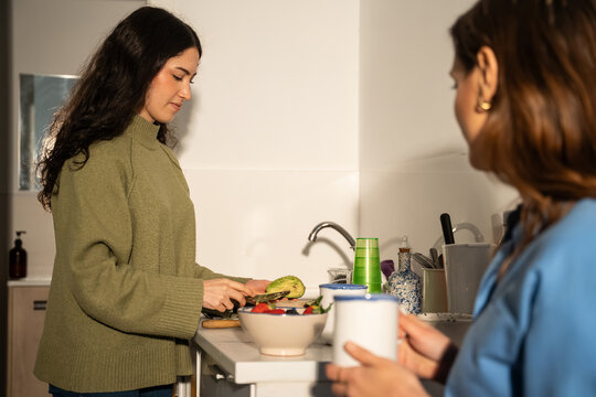 Women preparing breakfast in kitchen with coffee and fruit