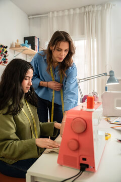 Multiethnic women sewing together in bright home atelier
