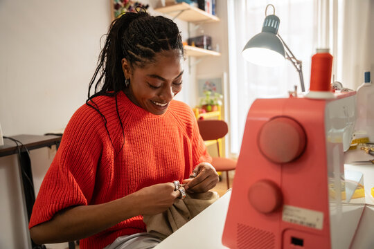 Black colombian woman sewing a garment by hand in a fashion atelier