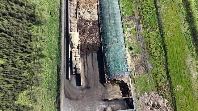Direct top-down view of sorted organic materials, wood chips, and biomass piles used for green energy production in a rural industrial setting.