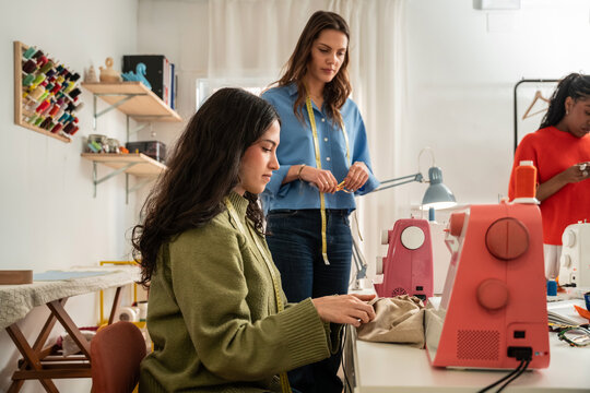 Multiethnic women sewing in bright fashion atelier studio