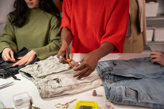Multiethnic women measuring denim and garment in atelier
