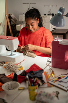 Black colombian woman sewing garment at fashion atelier worktable