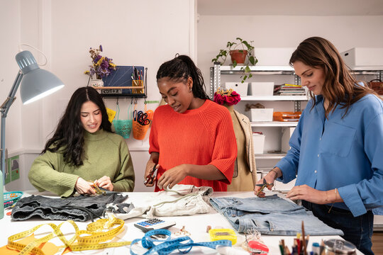 Multiethnic women working with fabric in atelier: upcycling concept