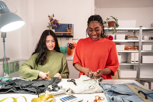 Multiethnic women sewing and upcycling jeans in atelier