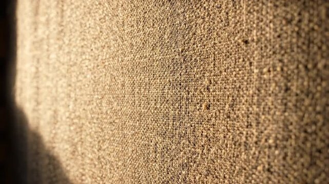 Warm textured fabric surface golden sunlight showing woven detail and soft shadowed gradient conveying cozy tactile warmth. warm textured fabric surface with golden light and soft shadow creating