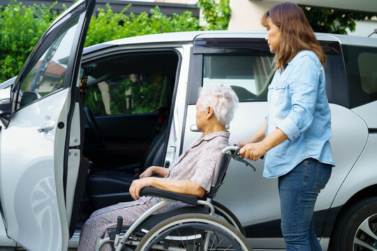 Caregiver help Asian elderly woman disability patient use wheelchair to get in car.