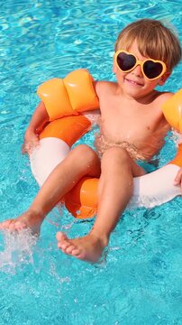 Happy child having fun in swimming pool on summer vacation. Slow motion. Vertical video