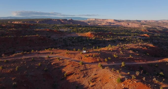 Red desert ridges and juniper covered hills in Grand Staircase Escalante Utah, drone dolly above truck camper