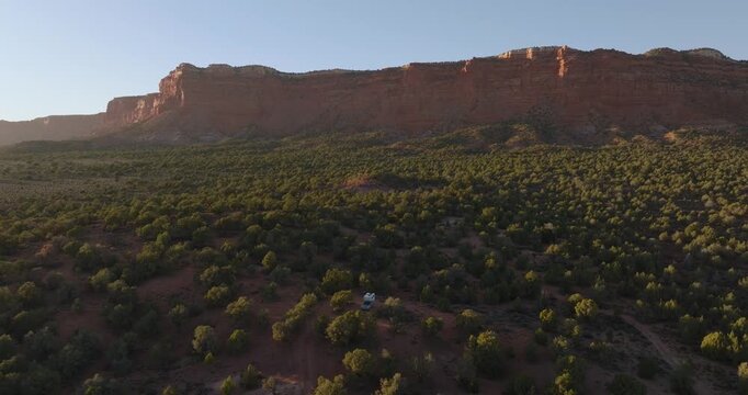 Wide aerial landscape of desert trees and towering red sandstone mesa cliffs near Kanab Utah, panoramic