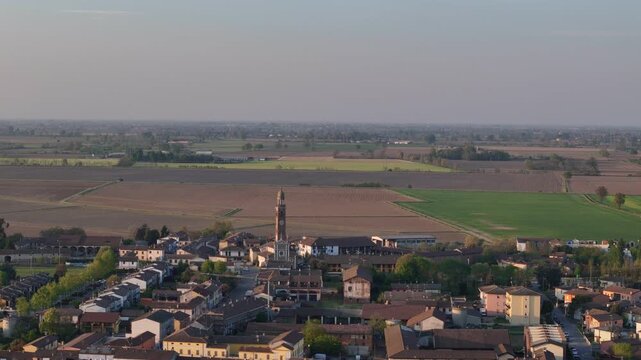 Spinadesco Cremona Lombardy Italy with parish church tower and residential core backed by irrigated arable fields, crop rotation parcels and canal network in Po Valley, aerial
