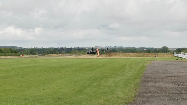 Black Robinson R44 Raven II helicopter hovering low to the ground stock footage