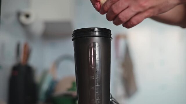 A person is preparing a mixture by placing ingredients into a container in a kitchen setting. The individual appears to be focused on ensuring the mixture is ready for further cooking steps