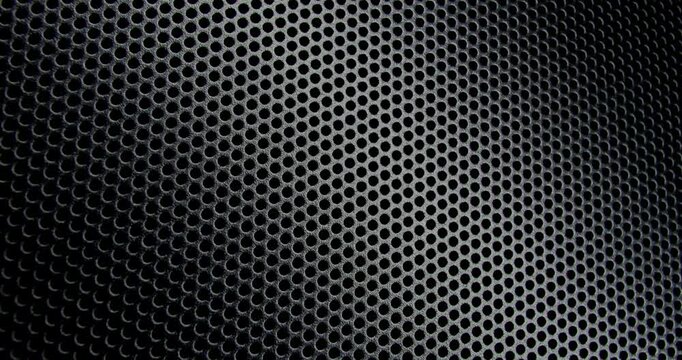 Black Perforated Metal Mesh. Smooth slow movement across extreme close-up of dark perforated metal grid with dramatic side lighting.