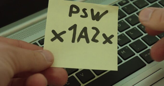 Close-up of a sticky note with a password placed on a laptop keyboard, illustrating insecure handling of login credentials.
