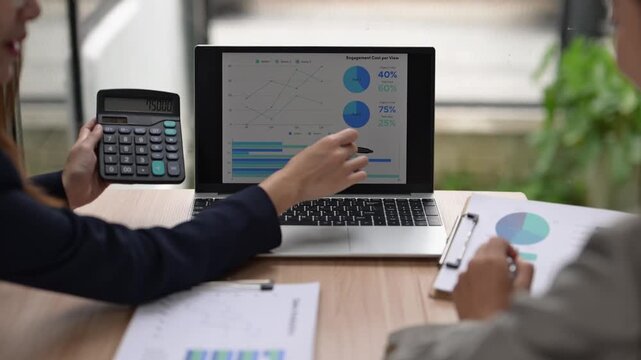 Businesswomen analyzing financial charts on laptop