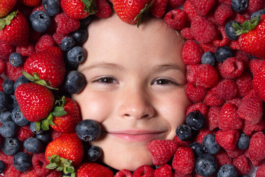 Healthy food for kids. Kids face with berries mix of strawberry, blueberry, raspberry, blackberry.
