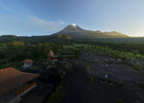 Aerial view of Bunker Kaliadem Merapi with traditional pavilions and people walking near the base of Mount Merapi volcano at sunrise Kecamatan Pakem, Daerah Istimewa Yogya, Indonesia.
