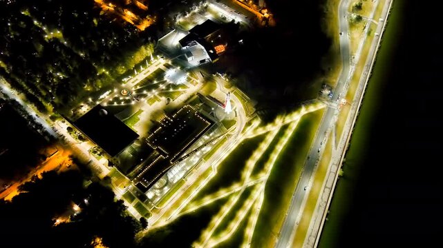 Kaluga, Russia. Tsiolkovsky State Museum of the History of Cosmonautics, its illuminated parabolic dome and Vostok rocket monument, Drone footage at night over the Oka River embankment. Drone footage