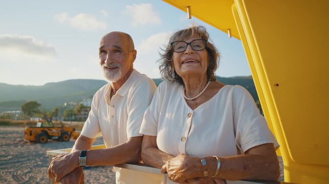 Elderly couple in their seventies enjoying a romantic moment together on the beach, watching the sunset from a lifeguard tower, sharing happiness and love during their summer vacation