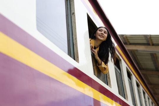 Young woman enjoying train journey looking out window while enjoying the scenic view during her travel.