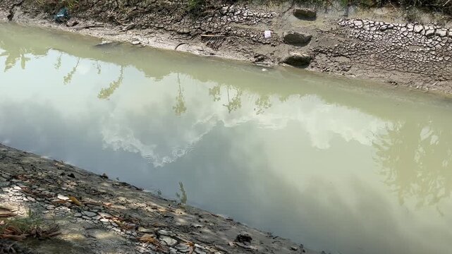 Dirty muddy river water with stone embankment wall