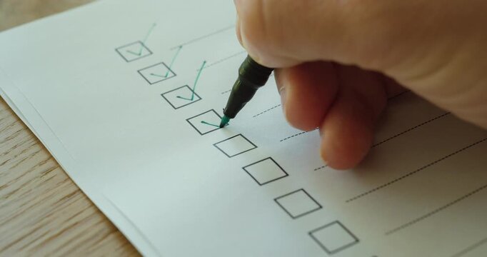 Close-up of a person marking checkboxes on a checklist, representing productivity, organization, and task completion.