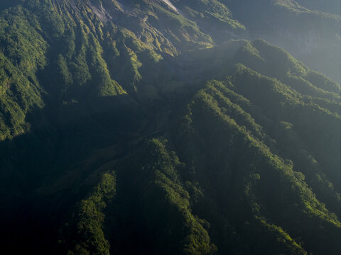 Aerial view of Bunker Kaliadem Merapi on the volcanic slopes of Mount Merapi with lush green ridges and morning mist in Kecamatan Pakem, Daerah Istimewa Yogya, Indonesia.