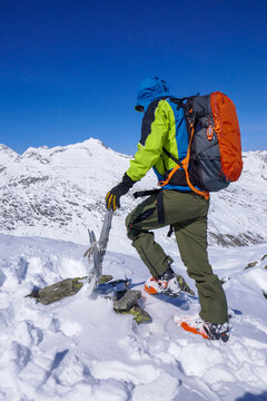 Alpinista tocca la croce di vetta in inverno