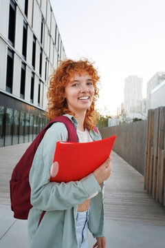 Young student smiling with red folder outdoors
