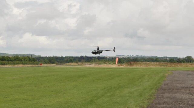 Black Robinson R44 Raven II helicopter hovering low to the ground stock footage