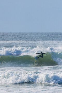 Surfer in a wetsuit riding a breaking wave, performing an active sport
