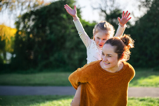 Mother and child playing in the park in sunlight, copy space