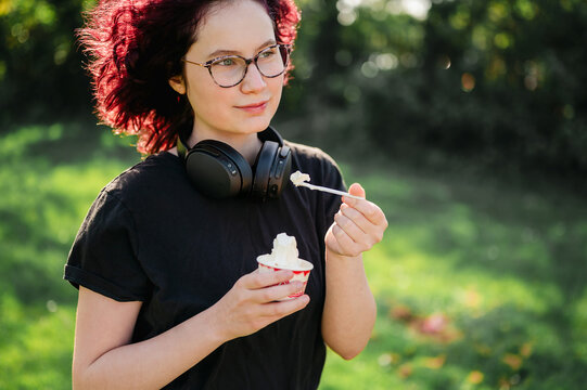 Teen age girl eating ice cream outdoors, summer time, copy space