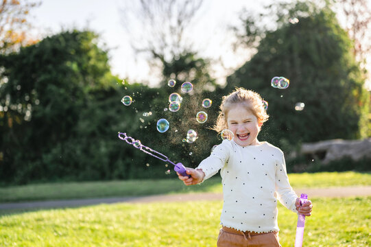 Girl playing with bubbles in sunlight outdoors
