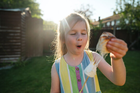 Girl reacting to sticky melted marshmallow in sunny backyard