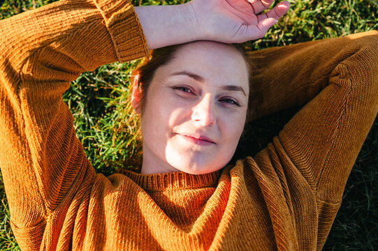 Woman relaxing lying on grass in warm sunlight
