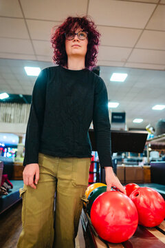 Teen age girl at bowling holding red ball in indoor alley