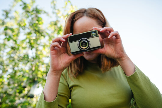 Woman photographing from low angle in sunny garden