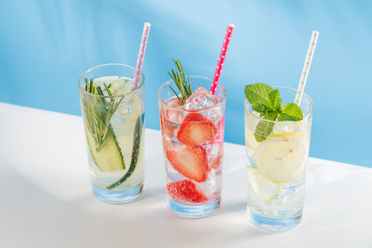 Set of fresh non alcoholic drinks with strawberry cucumber and lemon on blue background