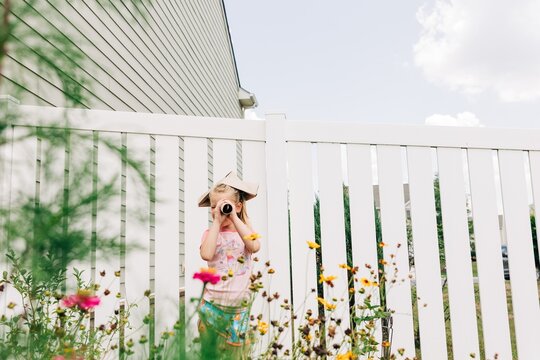 Girl playing make believe with paper hat in backyard