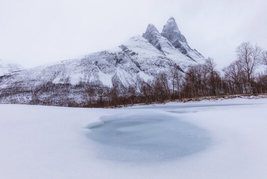 Snowy Mountain Peaks Above Frozen Lake with Ice Hole