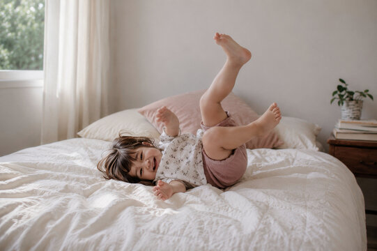 Playful little girl striking a funny pose on the bed.